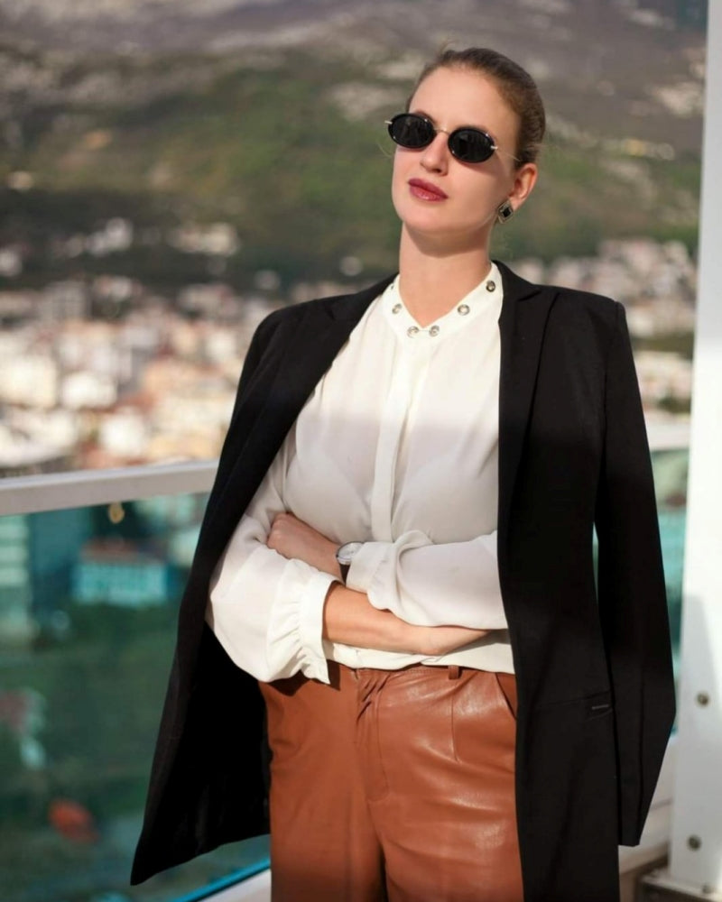 A person in a white shirt and black jacket in Montenegro in front of a lake